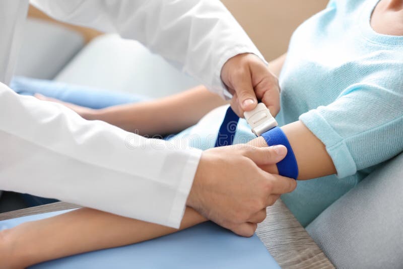Medico maschio che prepara il paziente per il sangue assorbe la clinica fotografia stock libera da diritti Medico maschio che prepara il paziente per il sangue assorbe la clinica fotografia stock libera da diritti