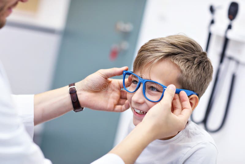 Medico maschio dell'ottico dell'optometrista di optometria del bambino esamina la vista del ragazzino fotografia stock