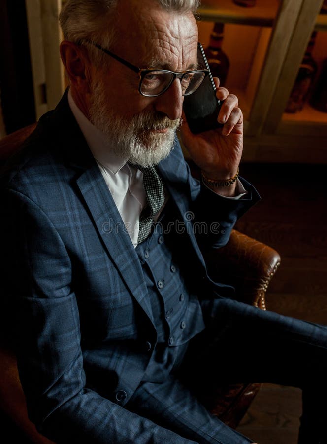Medico privato anziano con esperienza che parla sullo smartphone con il paziente all'interno fotografia stock Medico privato anziano con esperienza che parla sullo smartphone con il paziente all'interno fotografia stock