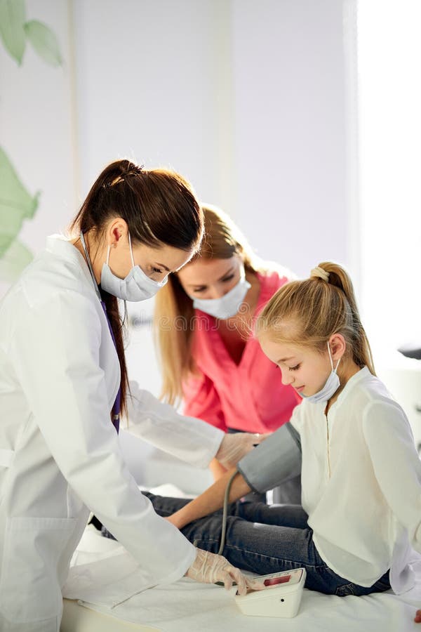 Medico professionista che misura la pressione sanguigna della ragazza usando il tonometro immagini stock libere da diritti