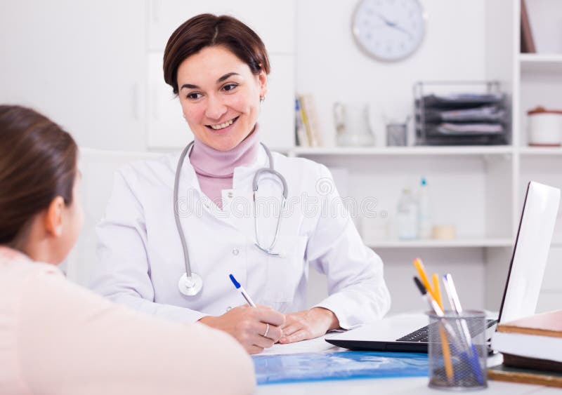 Medico riempie la carta paziente per la ragazza fotografia stock libera da diritti Medico riempie la carta paziente per la ragazza fotografia stock libera da diritti