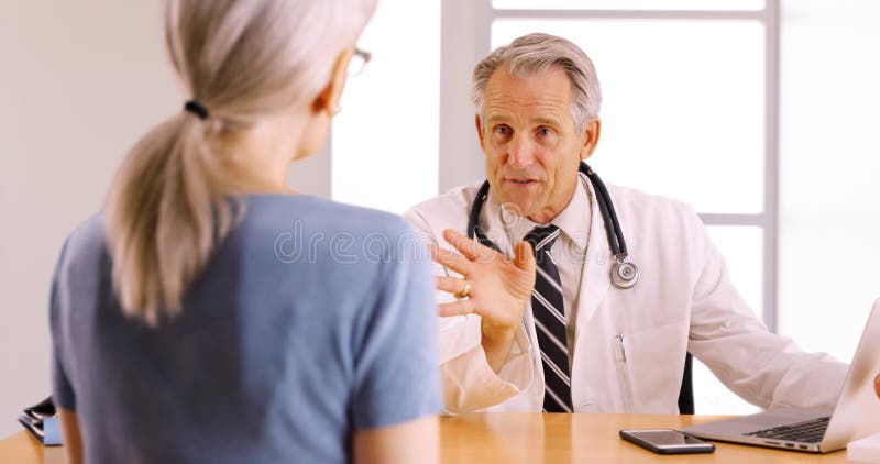 Medico senior sicuro che discute procedura della chirurgia con il paziente anziano della donna immagine stock Medico senior sicuro che discute procedura della chirurgia con il paziente anziano della donna immagine stock
