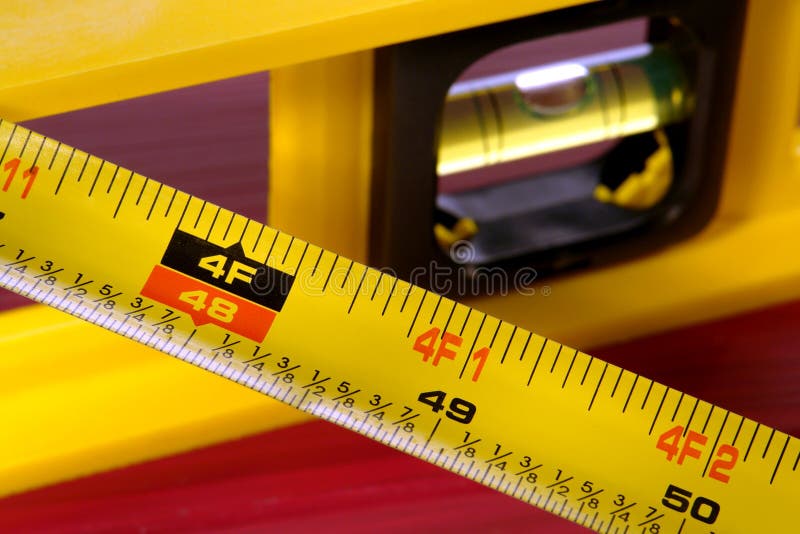 Construction bubble spirit level and retractable tape measure with inch and foot measurement markings. Construction bubble spirit level and retractable tape measure with inch and foot measurement markings