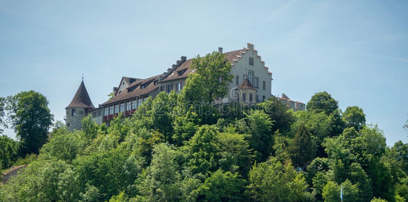 Medieval europe style castle among fresh green forest on top of hill with blue sky background