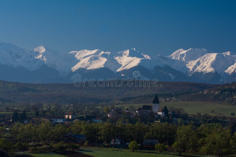 Hosman, medieval fortified church. Medieval fortified church in the saxon village Hosman, with the snowy Transylvanian Alps in the background royalty free stock photos Hosman, medieval fortified church. Medieval fortified church in the saxon village Hosman, with the snowy Transylvanian Alps in the background royalty free stock photos