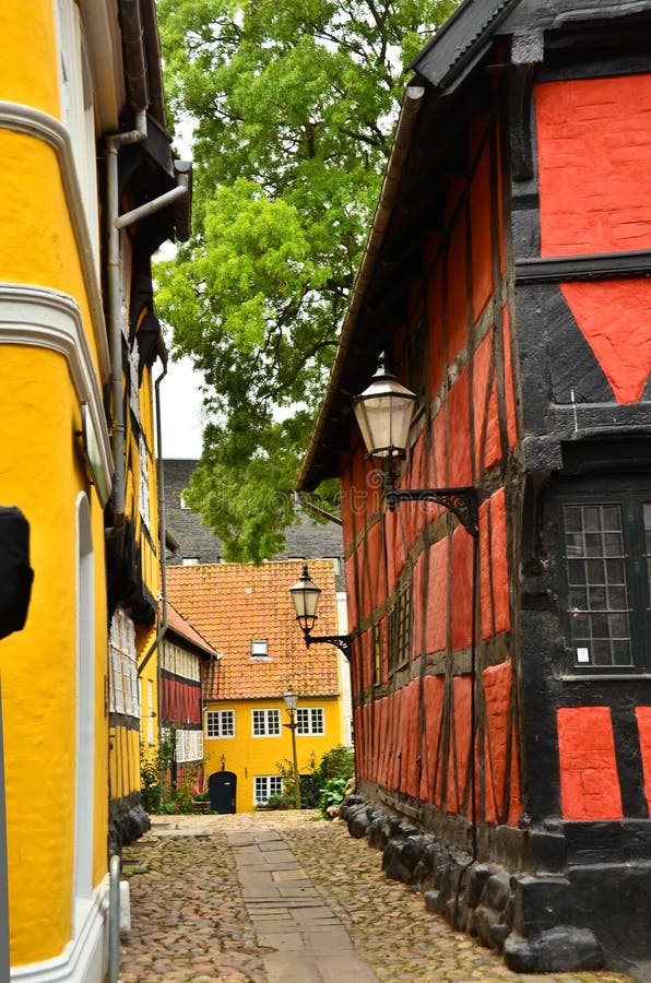 A medieval red frame house with an old fashioned lantern in a small lane stock images.