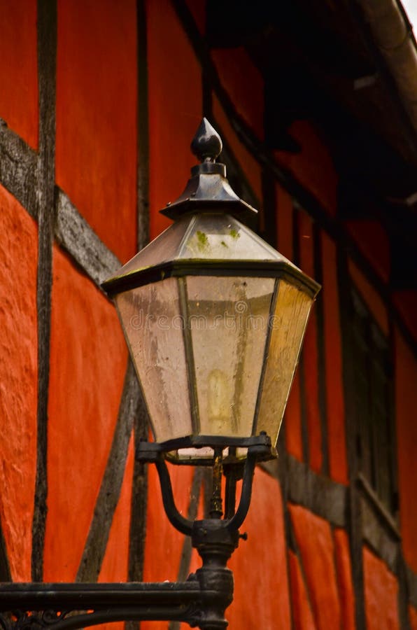 A medieval red frame house with an old fashioned lantern in a small lane royalty free stock image.