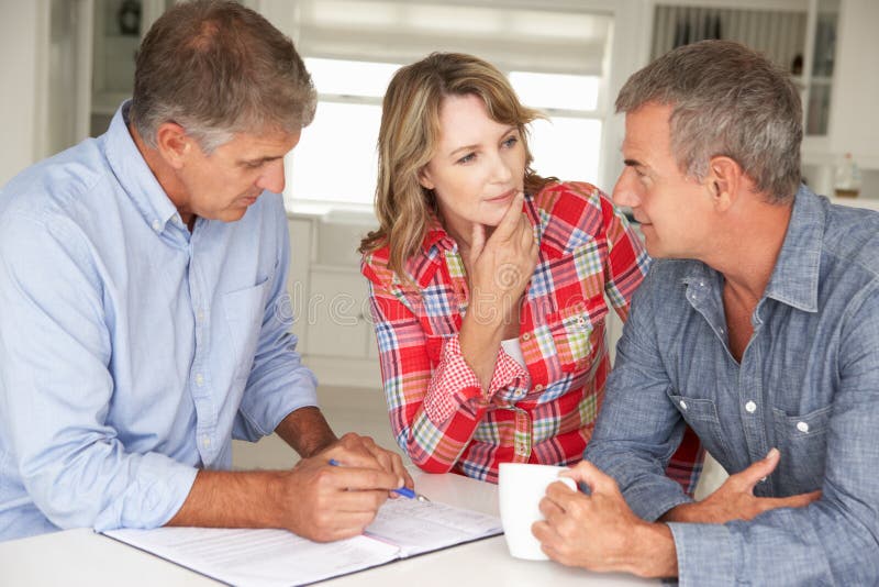 Medio leeftijdspaar met financiële adviseur thuis stock foto Medio leeftijdspaar met financiële adviseur thuis stock foto