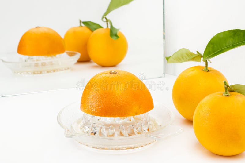 Medio naranja sobre una exprimidor y dos naranjas con hojas fotografía de archivo libre de regalías Medio naranja sobre una exprimidor y dos naranjas con hojas fotografía de archivo libre de regalías