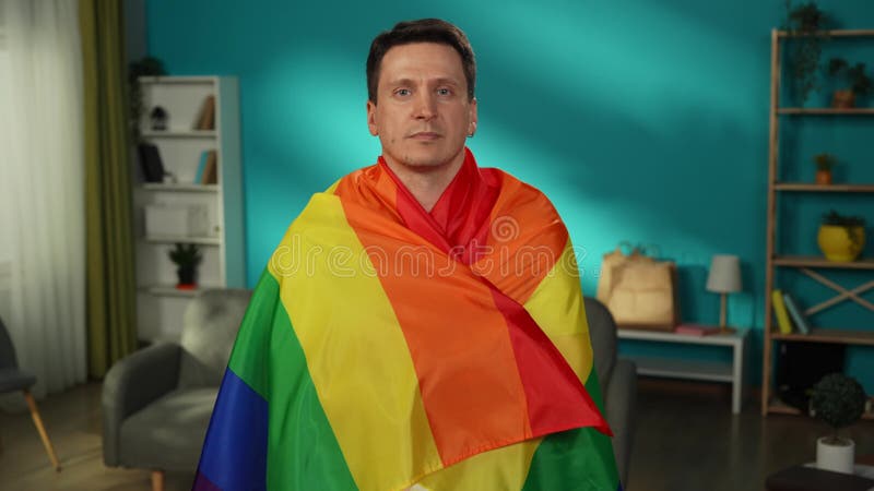 Medio video de una persona homosexual bisexual pansexual transexual mirando la cámara y envuelta en la bandera lgbt para