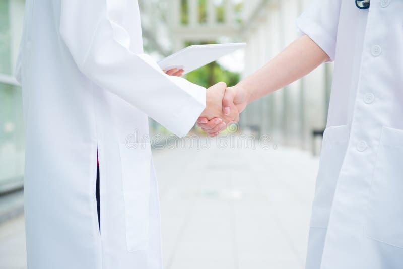 Two medical doctors shaking hands at hospital corridor, teamwork concept. Two medical doctors shaking hands at hospital corridor, teamwork concept.