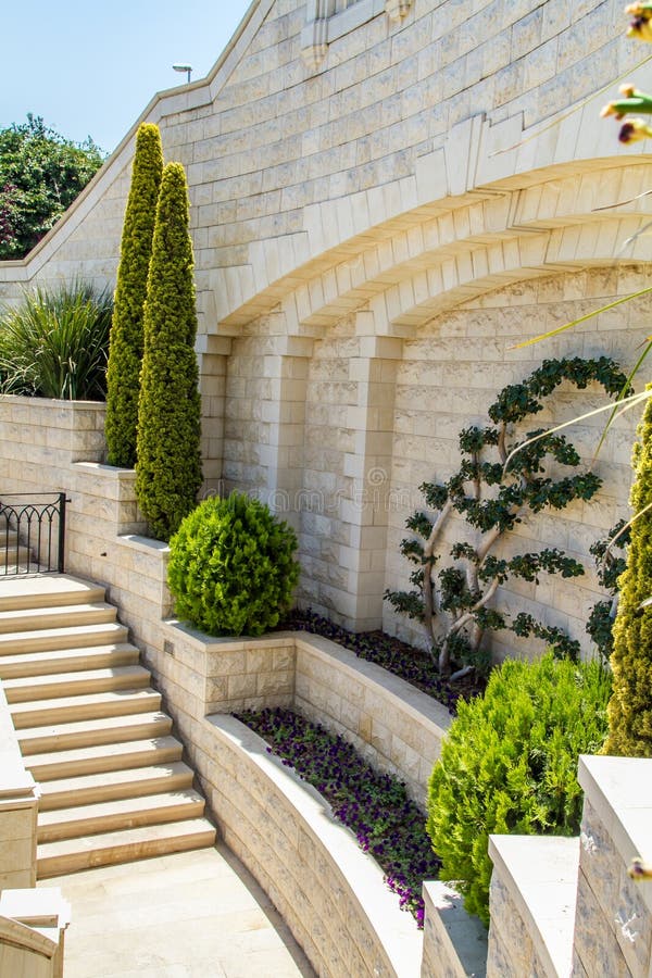 Mediterranean landscaped garden with a stone staircase. Trimmed trees and bushes near a white wall. Mediterranean landscaped garden with a stone staircase. Trimmed trees and bushes near a white wall