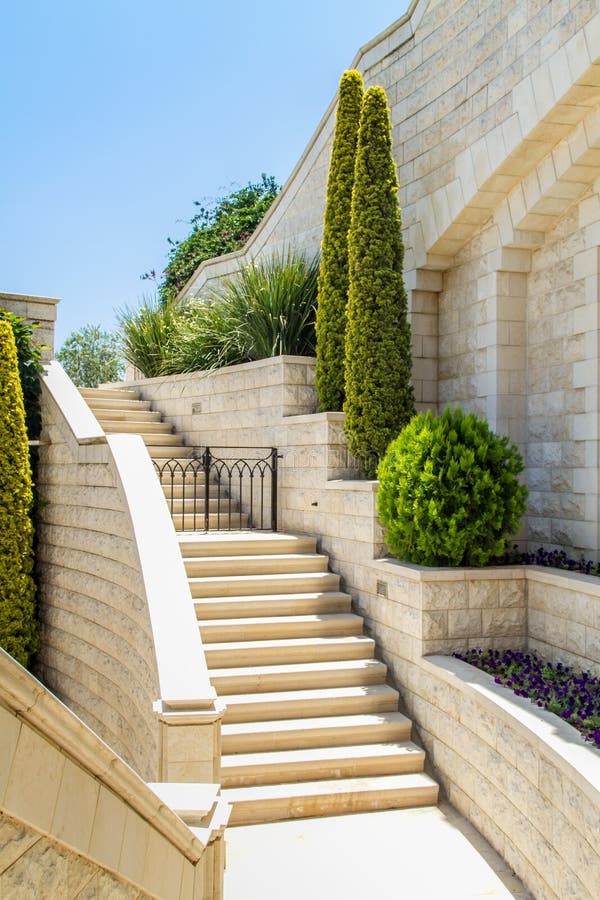 Mediterranean landscaped garden with a stone staircase. Trimmed trees and bushes near a white wall. Mediterranean landscaped garden with a stone staircase. Trimmed trees and bushes near a white wall