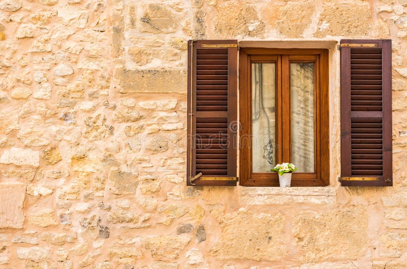 Mediterranean house with open window and rustic stone wall