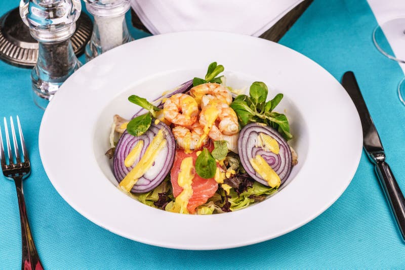 Mediterranean salad. grilled prawns, red onion rings, lemon peel, ginger root and vegetables dressed with olive oil royalty free stock images