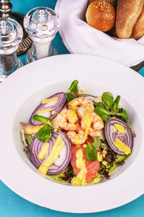 Mediterranean salad. grilled prawns, red onion rings, lemon peel, ginger root and vegetables dressed with olive oil stock photo