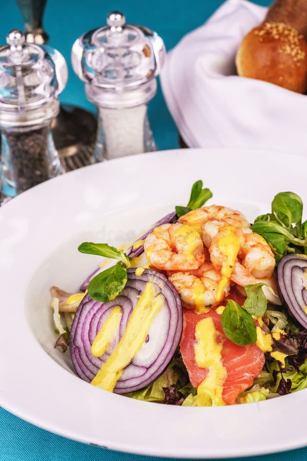 Mediterranean salad. grilled prawns, red onion rings, lemon peel, ginger root and vegetables dressed with olive oil royalty free stock image