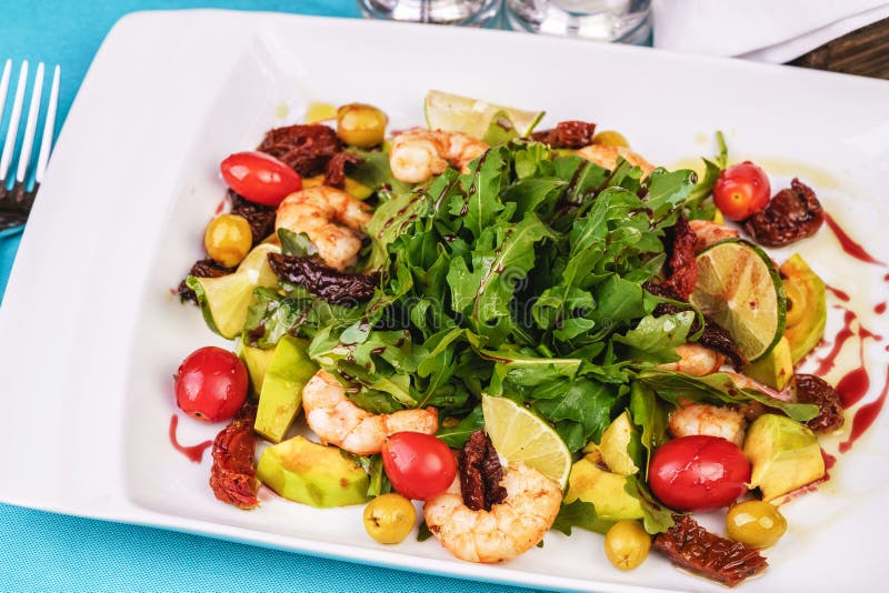 Mediterranean salad with grilled shrimps, cherry tomatoes, arugula, greens, avocado, lime, olives, balsamic sauce royalty free stock images