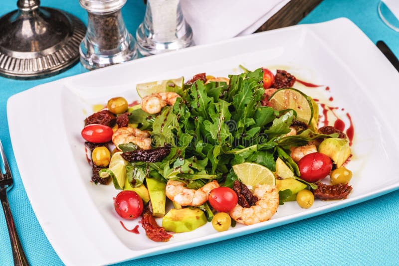 Mediterranean salad with grilled shrimps, cherry tomatoes, arugula, greens, avocado, lime, olives, balsamic sauce royalty free stock photography