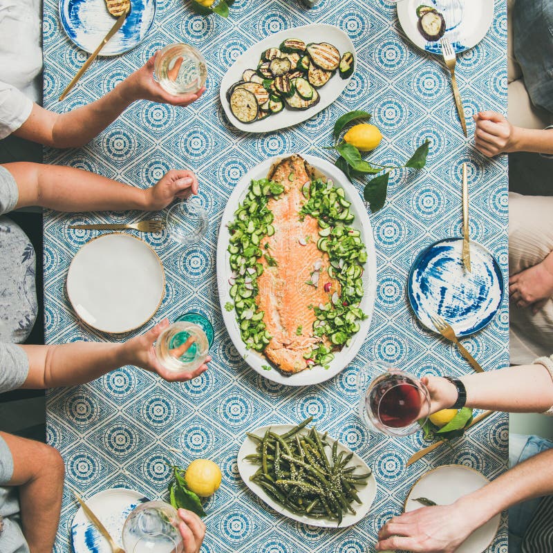 Mediterranean style dinner with cooked salmon, bread, lemonade, square crop