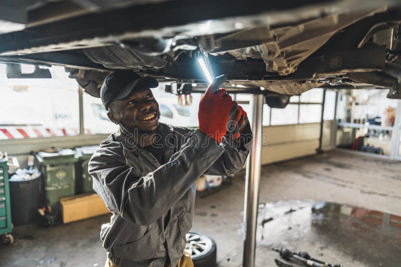 Medium Shot Of A Black Mechanic Lighting A Chassis Of A Car With A medium-shot-of-a-black-mechanic-lighting-a-chassis-of-a-car-with-a