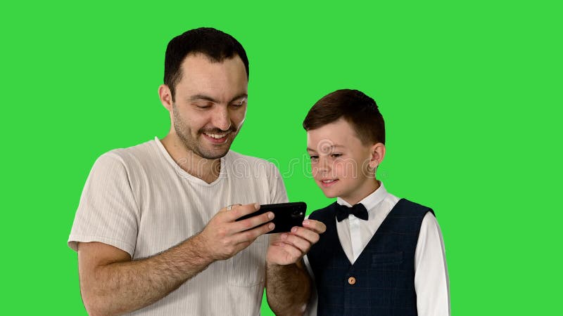 Happy father and son watching something on the phone and smiling on a Green Screen, Chroma Key.