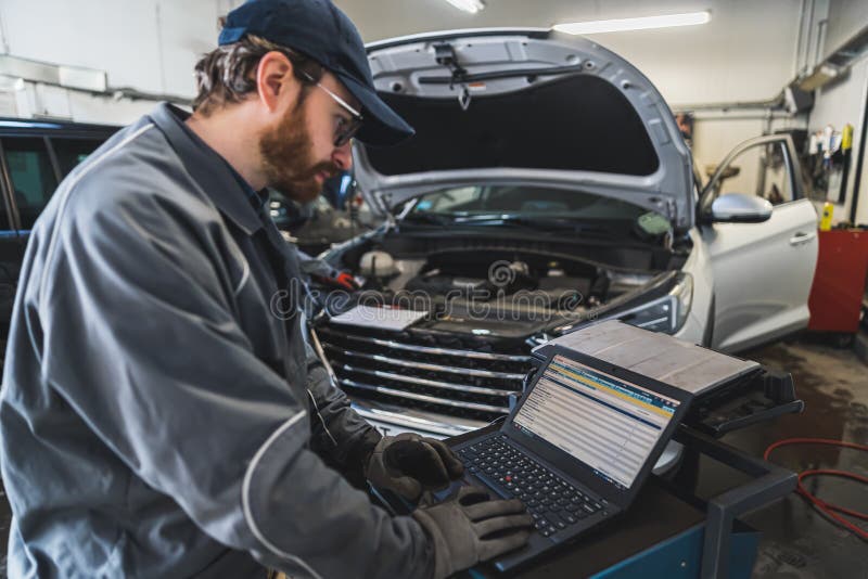 Medium Shot of a Mechanic Doing Car Computer Diagnostics. Repair Shop