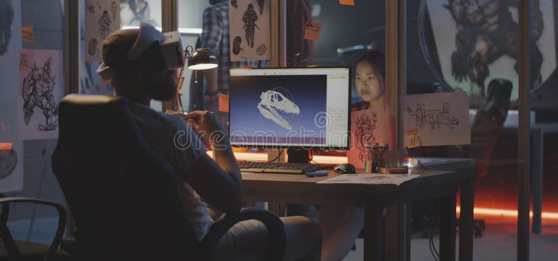 Man modeling dinosaur skull on computer. Medium shot of a VR headset wearing young men modeling dinosaur skull on computer stock images Man modeling dinosaur skull on computer. Medium shot of a VR headset wearing young men modeling dinosaur skull on computer stock images