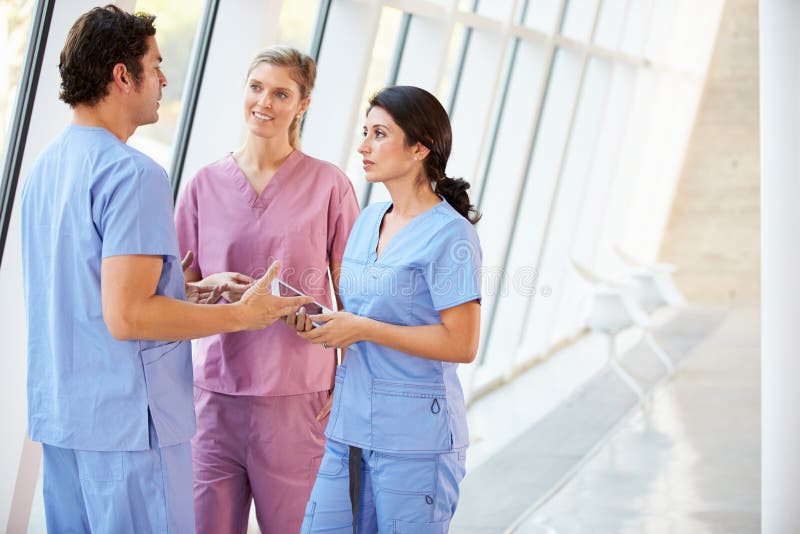 Medizinisches Personal, das im Krankenhaus-Korridor mit Digital-Tablette spricht lizenzfreies stockfoto Medizinisches Personal, das im Krankenhaus-Korridor mit Digital-Tablette spricht lizenzfreies stockfoto