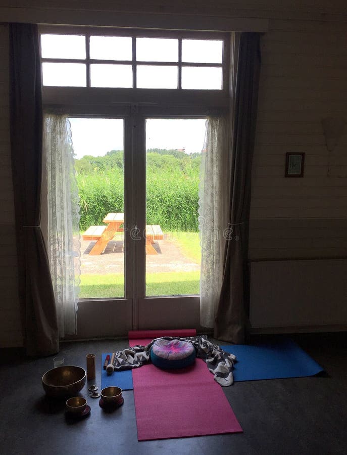 Medling av yogaskudde på trägolv i ett hem med fönster Träd som visas utanför fönstret Lokal för kopiering arkivbild Medling av yogaskudde på trägolv i ett hem med fönster Träd som visas utanför fönstret Lokal för kopiering arkivbild