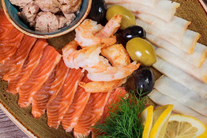 MEERESFRÜCHTE-SERVIERPLATTE Frische Dorschleber, Lachs, Garnele, ScheibenFischfilet, verziert mit Kraut, Zitrone und Oliven stockfotos MEERESFRÜCHTE-SERVIERPLATTE Frische Dorschleber, Lachs, Garnele, ScheibenFischfilet, verziert mit Kraut, Zitrone und Oliven stockfotos