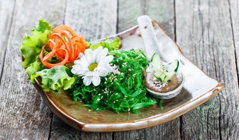 Meerespflanzen-Salat wakame in der Platte mit Essstäbchen auf Bambusmatte Japanische Küche - gesunde Meeresfrüchte