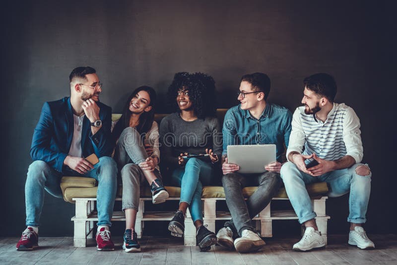Meertnische universitaire studenten die samen studeren Jongeren die met tests en gadgets werken, op de bank zitten stock foto Meertnische universitaire studenten die samen studeren Jongeren die met tests en gadgets werken, op de bank zitten stock foto
