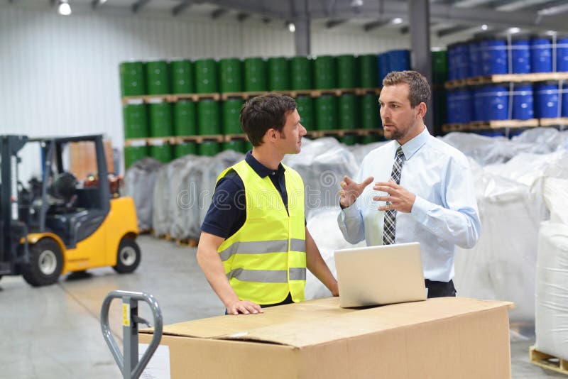 meeting of the manager and worker in the warehouse - forklift and interior of the industrial building