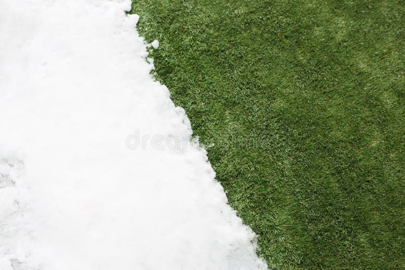 Meeting snow on green grass close up - between winter and spring concept background