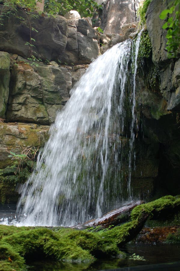 A waterfall cascading over a rock edge into a mossy pit. A waterfall cascading over a rock edge into a mossy pit.