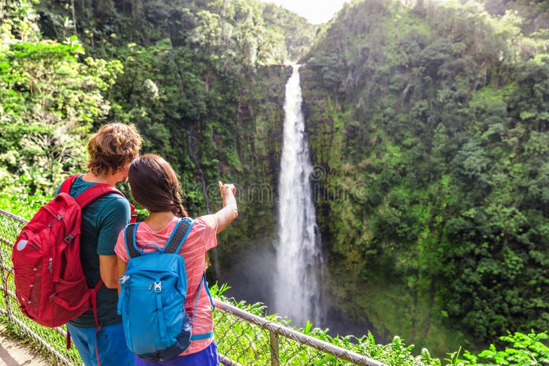 Mehrere Touristen weisen auf den Wasserfall von Hawaii hin