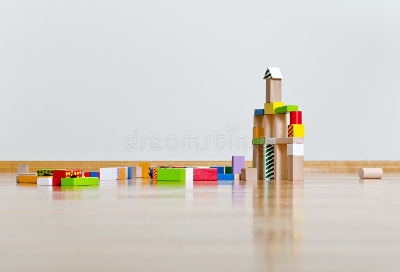 Multicolored building blocks on wooden floor against white wall. Multicolored building blocks on wooden floor against white wall