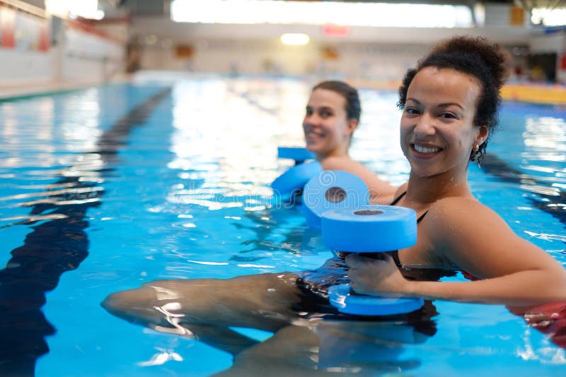 Mehrrassisches Paar, das in einem Schwimmbad eine Aerobic-Klasse besucht