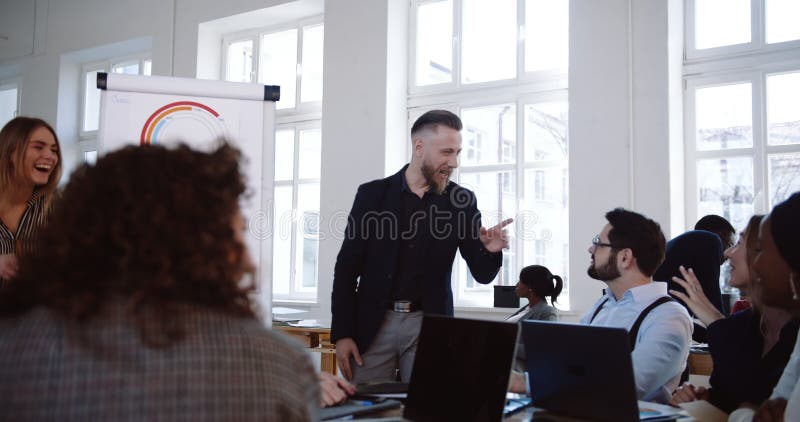 Meio feliz homem de negócios envelhecido que conduz a discussão ativa no seminário moderno do escritório com os empregados incorp