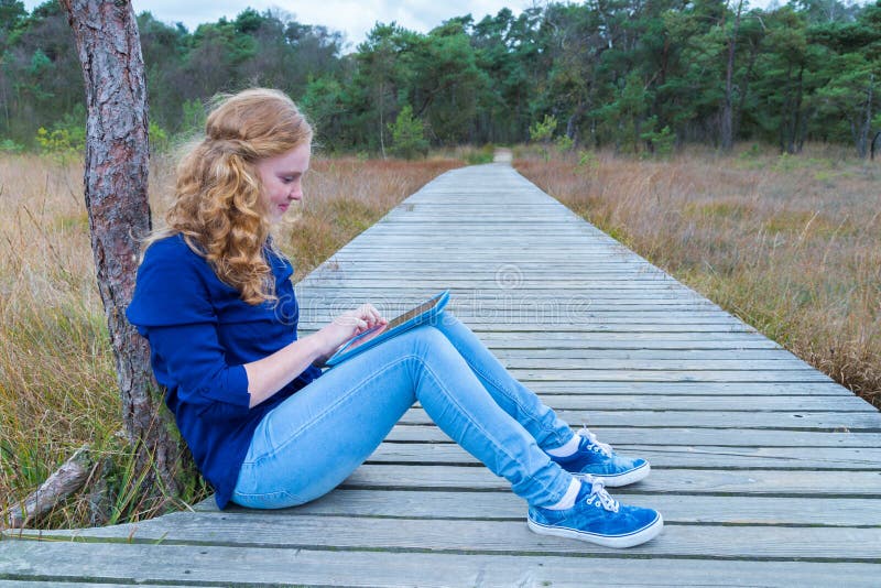 Meisje dat aan tabletcomputer werkt op weg in aard royalty-vrije stock afbeeldingen Meisje dat aan tabletcomputer werkt op weg in aard royalty-vrije stock afbeeldingen