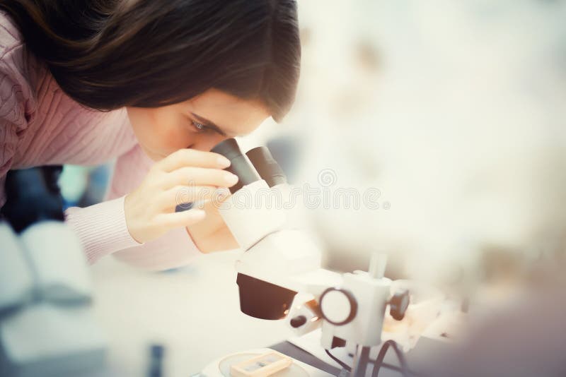 Meisje dat door een microscoop kijkt royalty-vrije stock afbeelding Meisje dat door een microscoop kijkt royalty-vrije stock afbeelding