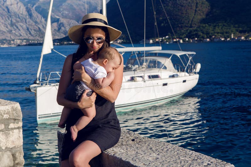 Meisje in de hoedenzitting met een baby naast een grote boot royalty-vrije stock afbeeldingen Meisje in de hoedenzitting met een baby naast een grote boot royalty-vrije stock afbeeldingen