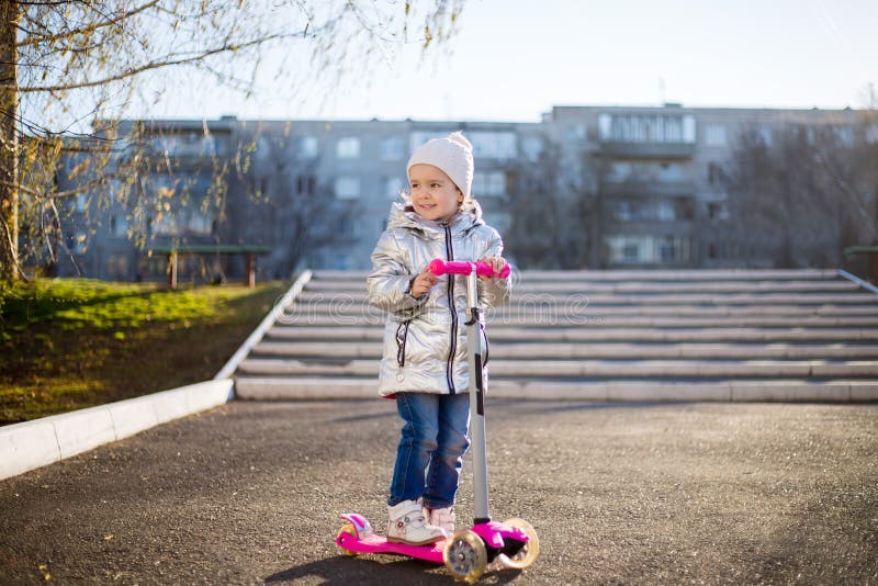 Meisje die een autoped in het Park berijden op een Zonnige de lentedag Actieve vrije tijd en openluchtsport voor kinderen stock foto Meisje die een autoped in het Park berijden op een Zonnige de lentedag Actieve vrije tijd en openluchtsport voor kinderen stock foto