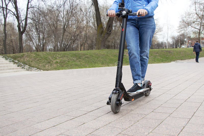 Meisje die een elektrische autoped in de parkweg berijden met een actiecamera Technologisch milieuvriendelijk vervoer modern stock afbeeldingen Meisje die een elektrische autoped in de parkweg berijden met een actiecamera Technologisch milieuvriendelijk vervoer modern stock afbeeldingen