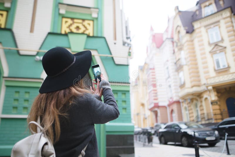 Meisje die een straatfoto op de telefoon fotograferen Een toeristenmeisje maakt een foto van architectuur op een smartphone stock fotografie Meisje die een straatfoto op de telefoon fotograferen Een toeristenmeisje maakt een foto van architectuur op een smartphone stock fotografie