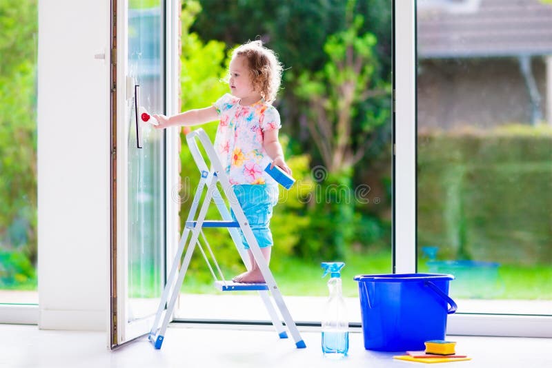 Meisje die een venster wassen stock afbeeldingen Meisje die een venster wassen stock afbeeldingen