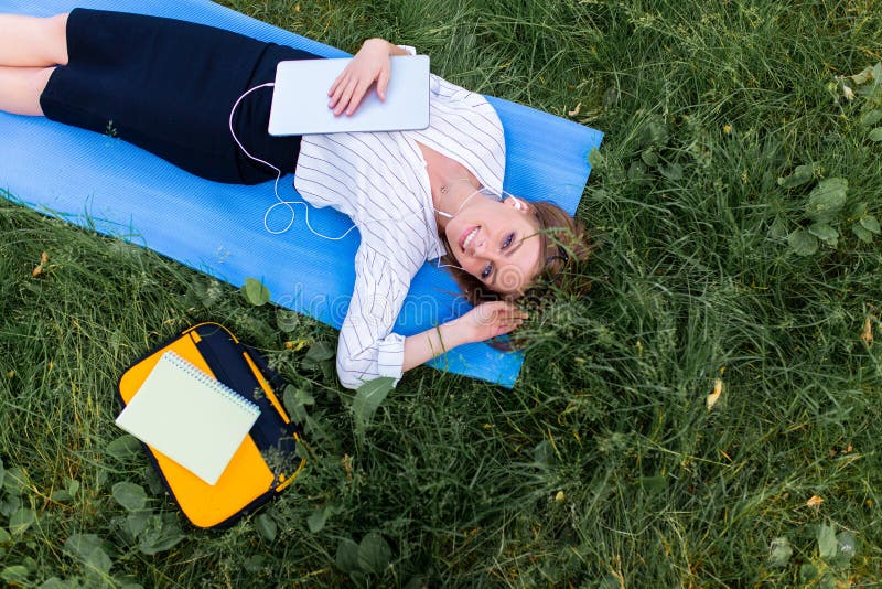 Meisje die in het park die op het gras met laptop rusten en aan muziek luisteren liggen Bovenkant wiew royalty-vrije stock foto's Meisje die in het park die op het gras met laptop rusten en aan muziek luisteren liggen Bovenkant wiew royalty-vrije stock foto's