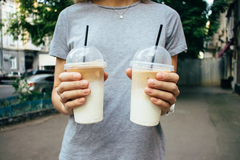 Meisje die koffie twee lattes in plastic transparante koppen houden stock afbeelding Meisje die koffie twee lattes in plastic transparante koppen houden stock afbeelding