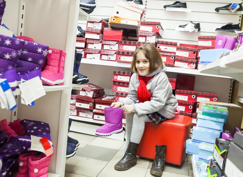 Meisje die schoenen in kinderen` s opslag proberen stock foto Meisje die schoenen in kinderen` s opslag proberen stock foto